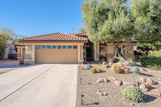 mediterranean / spanish home featuring concrete driveway, a tiled roof, an attached garage, and stucco siding