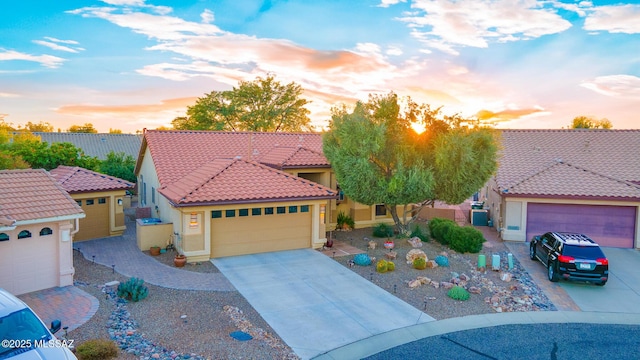 mediterranean / spanish-style house featuring an attached garage, a tiled roof, concrete driveway, and stucco siding