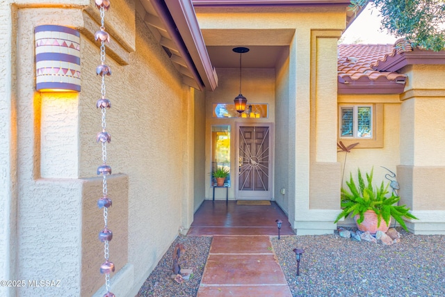 view of exterior entry with a tiled roof and stucco siding