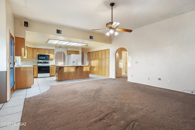 kitchen featuring arched walkways, white appliances, visible vents, open floor plan, and light countertops