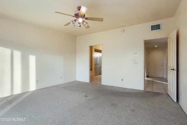 spare room with a ceiling fan, visible vents, and light colored carpet