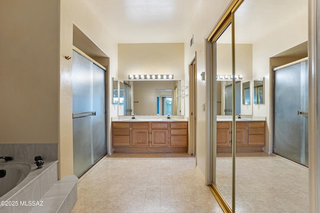 bathroom featuring a garden tub, double vanity, a sink, and a shower stall