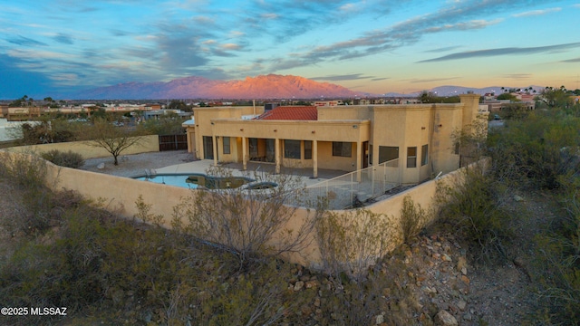 back of house featuring a patio area, a fenced backyard, a mountain view, and stucco siding