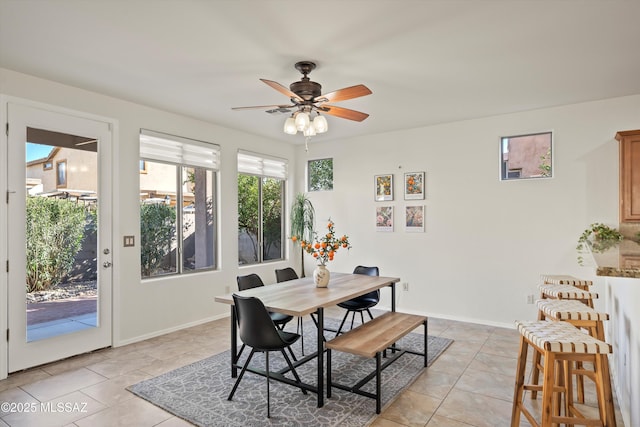 dining room with ceiling fan, baseboards, and light tile patterned flooring