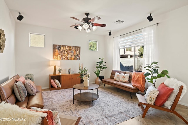 living room with ceiling fan, visible vents, and a wealth of natural light