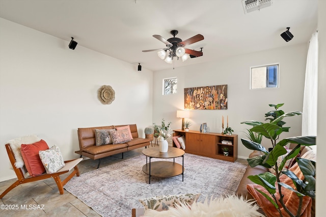 living area with ceiling fan, visible vents, and baseboards