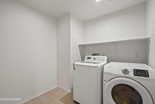 laundry room with light tile patterned floors, laundry area, baseboards, and washer and dryer