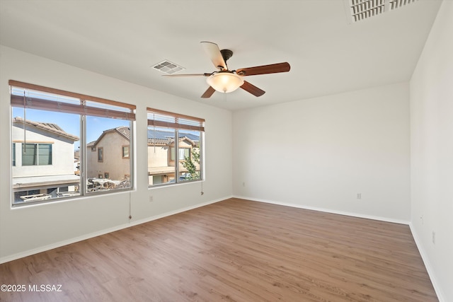 spare room featuring visible vents, ceiling fan, baseboards, and wood finished floors