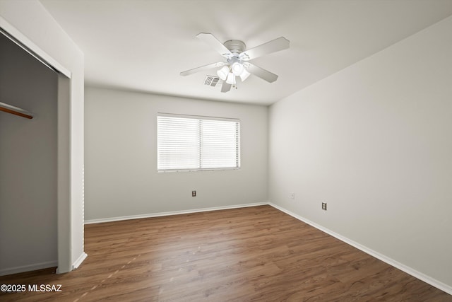 unfurnished bedroom with wood finished floors, a ceiling fan, visible vents, baseboards, and a closet