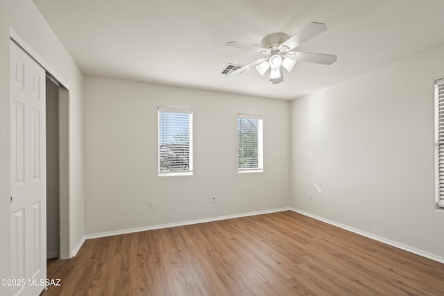 unfurnished bedroom featuring a closet, wood finished floors, visible vents, and baseboards