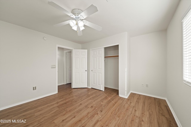 unfurnished bedroom with baseboards, multiple windows, a closet, and light wood-style floors