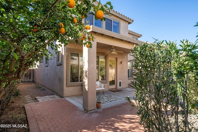 back of property featuring a ceiling fan, a tile roof, fence, and stucco siding