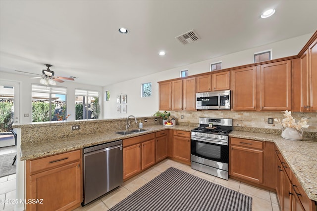 kitchen with a peninsula, a sink, visible vents, appliances with stainless steel finishes, and decorative backsplash