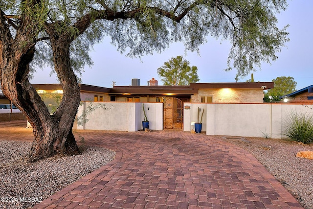 view of front facade with a fenced front yard, a chimney, and decorative driveway