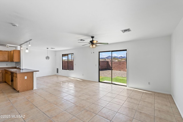 interior space featuring dark countertops, visible vents, brown cabinetry, open floor plan, and a peninsula