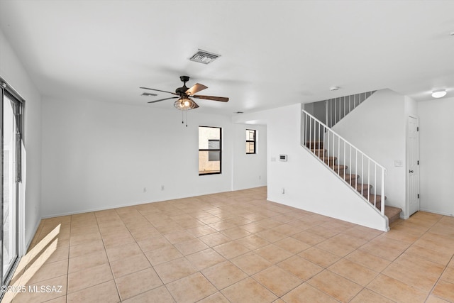 empty room with light tile patterned floors, ceiling fan, stairs, and visible vents