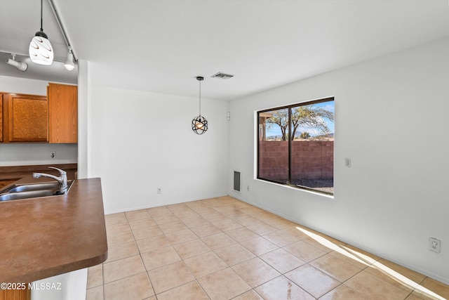 unfurnished dining area featuring light tile patterned floors, a sink, visible vents, and rail lighting