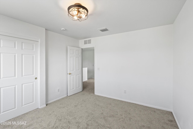 unfurnished bedroom featuring visible vents, light carpet, and baseboards