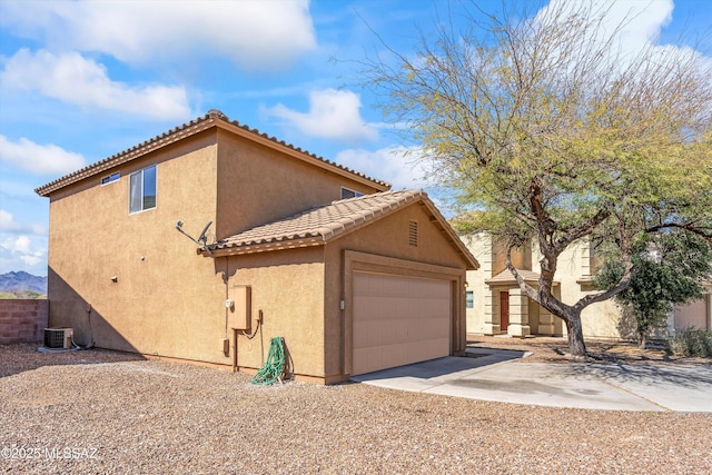 view of home's exterior with an outbuilding, stucco siding, concrete driveway, an attached garage, and a tiled roof