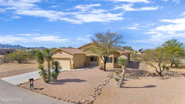 view of front of house with concrete driveway, a tiled roof, an attached garage, a mountain view, and stucco siding