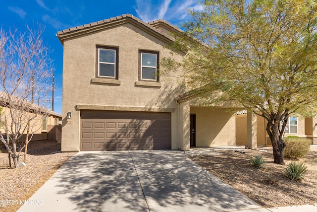 view of front of property featuring an attached garage, a tiled roof, concrete driveway, and stucco siding