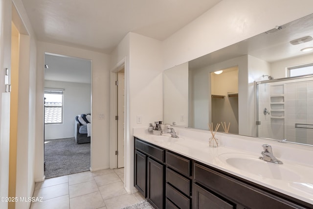 full bath featuring double vanity, a stall shower, tile patterned flooring, and a sink