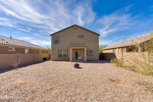 back of house with an outdoor fire pit, a fenced backyard, central AC unit, and stucco siding