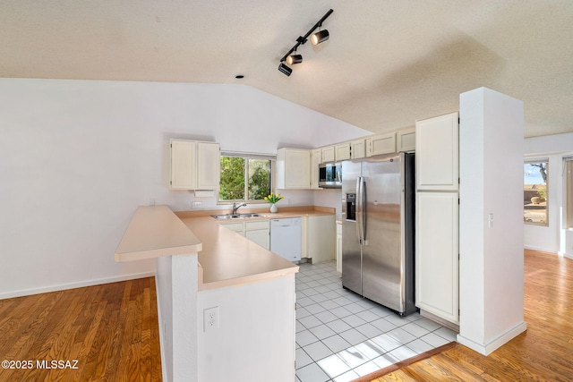 9990 E Mary Dr, Tucson, AZ 85730 - kitchen with stainless steel appliances, light countertops, track lighting, vaulted ceiling, and a peninsula