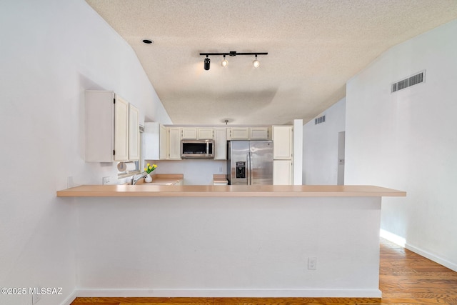 9990 E Mary Dr, Tucson, AZ 85730 - kitchen with a peninsula, appliances with stainless steel finishes, a textured ceiling, and visible vents