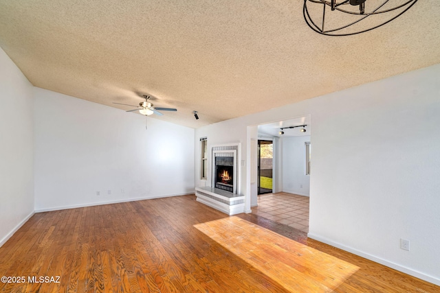 9990 E Mary Dr, Tucson, AZ 85730 - unfurnished living room with a ceiling fan, wood finished floors, a textured ceiling, a fireplace, and baseboards