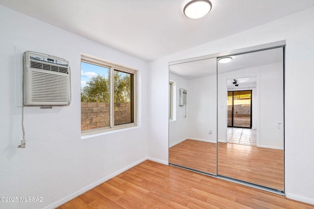 9990 E Mary Dr, Tucson, AZ 85730 - unfurnished bedroom with a wall mounted air conditioner, baseboards, and light wood-style flooring