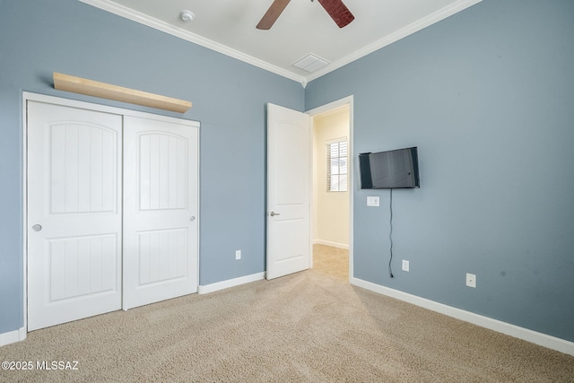 unfurnished bedroom with carpet floors, visible vents, baseboards, ornamental molding, and a closet