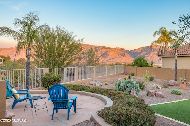 patio terrace at dusk with a fenced backyard and a mountain view