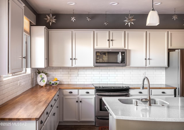 kitchen featuring wood counters, appliances with stainless steel finishes, decorative backsplash, and a sink