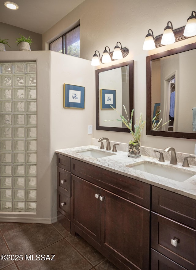 full bath with double vanity, tile patterned flooring, baseboards, and a sink