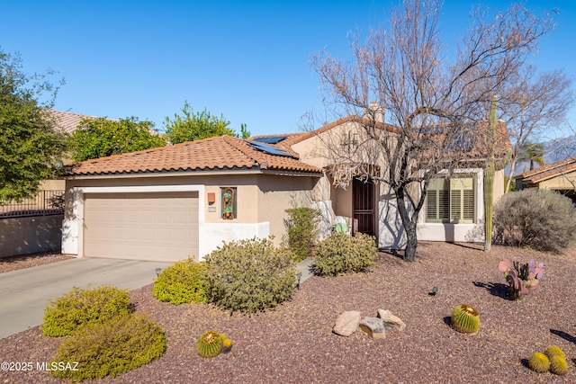 mediterranean / spanish-style house featuring solar panels, stucco siding, concrete driveway, a garage, and a tiled roof