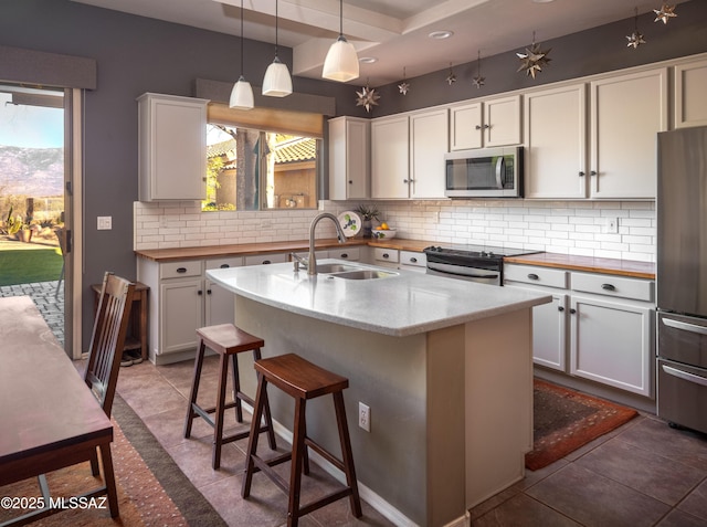 kitchen featuring a sink, white cabinets, appliances with stainless steel finishes, backsplash, and pendant lighting