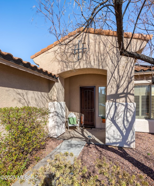 doorway to property featuring a tiled roof and stucco siding