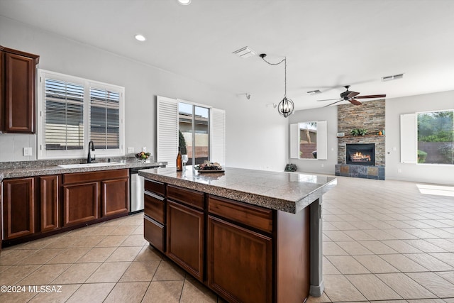 kitchen featuring light tile patterned floors, tile countertops, a stone fireplace, a sink, and visible vents