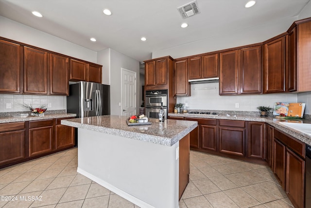 kitchen with light tile patterned floors, a kitchen island, visible vents, and stainless steel appliances