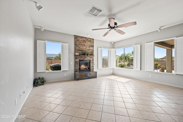 unfurnished living room featuring baseboards, visible vents, a ceiling fan, a fireplace, and light tile patterned flooring