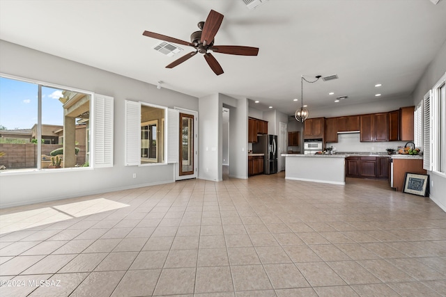 unfurnished living room featuring a healthy amount of sunlight, visible vents, and light tile patterned floors