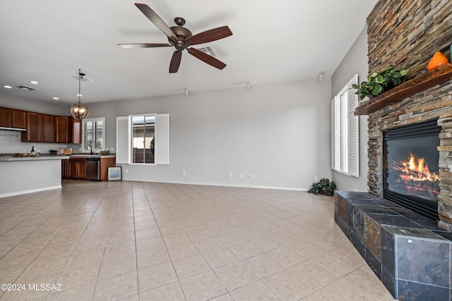 unfurnished living room featuring light tile patterned floors, baseboards, a wealth of natural light, and a stone fireplace