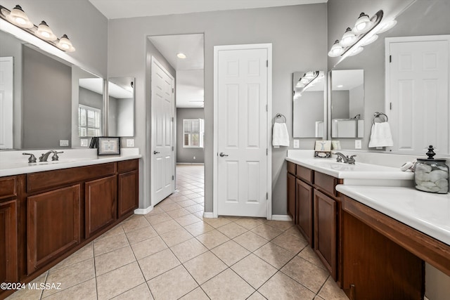 full bathroom featuring tile patterned flooring, two vanities, a sink, and baseboards