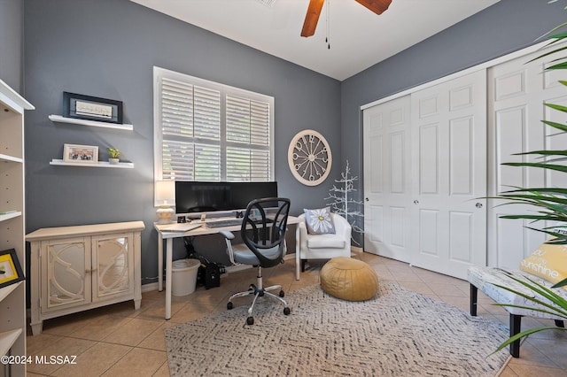 tiled office space featuring ceiling fan and baseboards