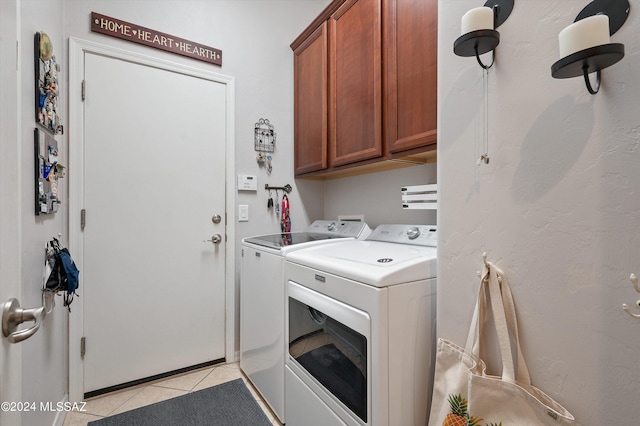 washroom with cabinet space, light tile patterned floors, and washing machine and clothes dryer