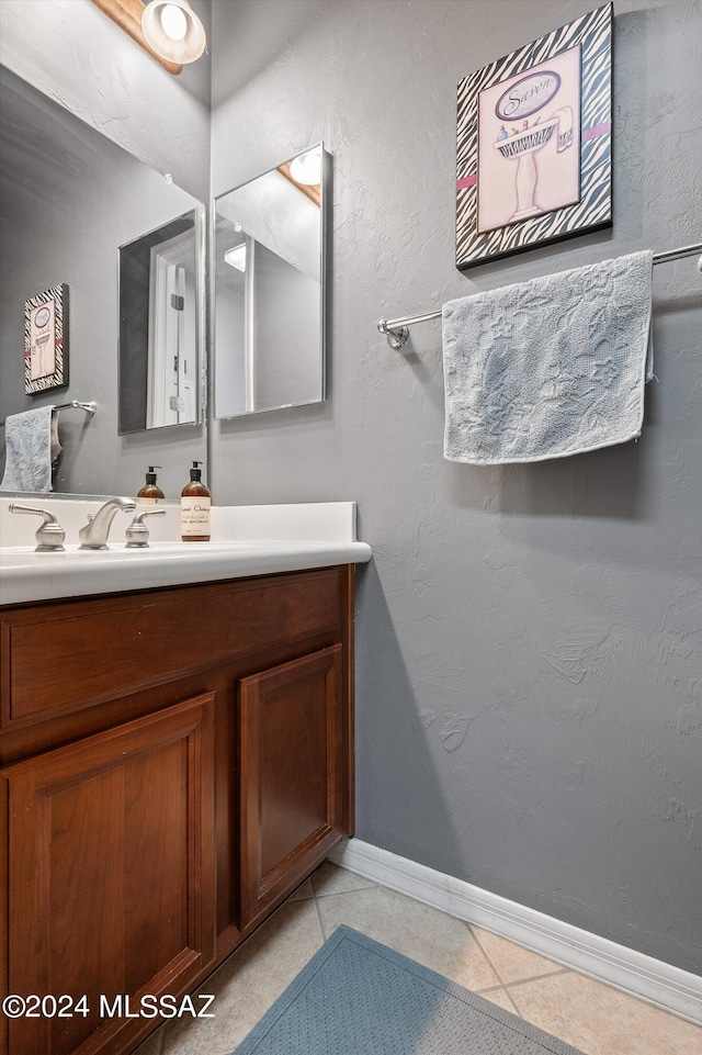 bathroom featuring tile patterned flooring, a textured wall, vanity, and baseboards