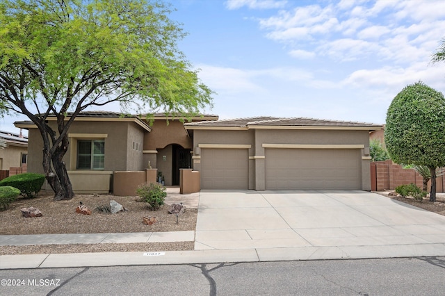 view of front facade featuring a garage, driveway, a tile roof, fence, and stucco siding