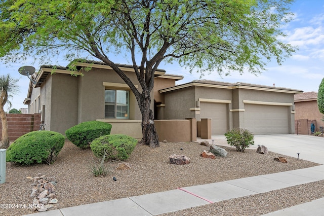 view of front of home featuring a garage, concrete driveway, fence, and stucco siding