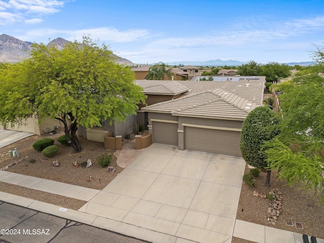 view of front of property with a tile roof, stucco siding, concrete driveway, an attached garage, and a mountain view